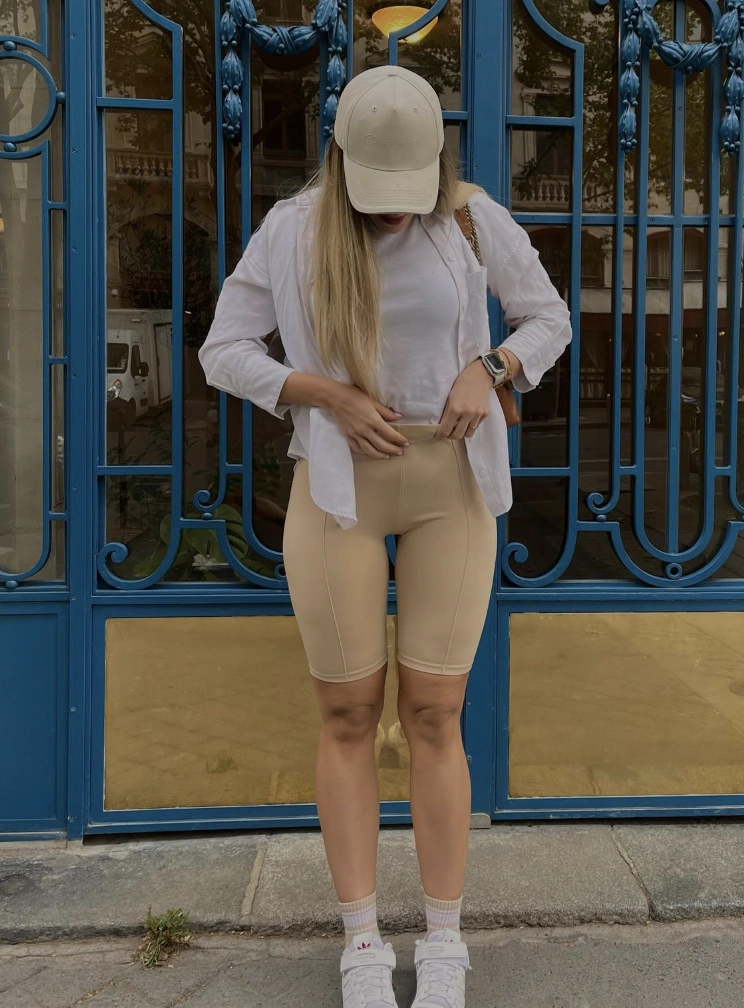 A casual outfit featuring beige biker shorts and a white cropped top, perfect for warm-weather outings or active wear.