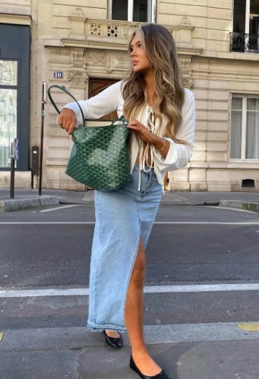 Casual denim maxi skirt with a side slit, paired with a white top and green handbag, perfect for daytime outings.