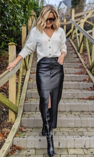 Black faux leather pencil skirt with a front slit, paired with a light cardigan; perfect for casual outings or stylish events.