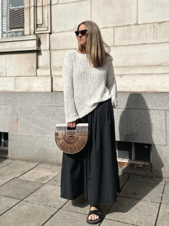 Casual black maxi skirt paired with a light, textured cream sweater; perfect for everyday outings or relaxed gatherings.