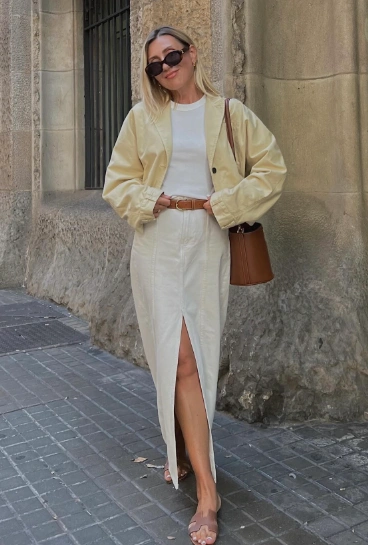 A cream maxi skirt featuring a front slit, paired with a white top and oversized light jacket, perfect for casual outings.