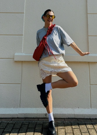 A lace skirt outfit featuring a light beige lace skirt, gray casual top, and black chunky shoes, ideal for a stylish daytime outing.