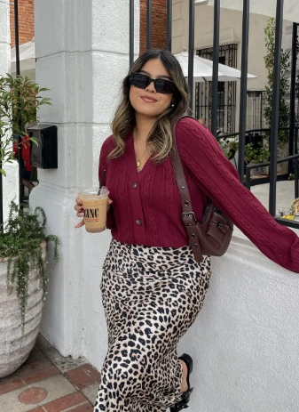 A casual leopard print midi skirt paired with a burgundy cable-knit cardigan, perfect for brunch or a casual outing.