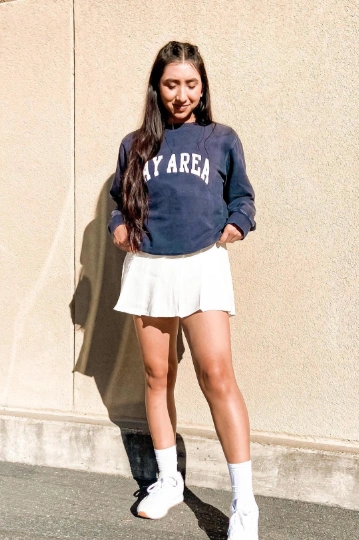 A casual outfit featuring a white tennis skirt and a navy sweatshirt with