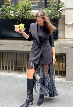 Black lace skirt layered under a tailored blazer, featuring a high-low hem. Ideal for formal events or stylish outings.
