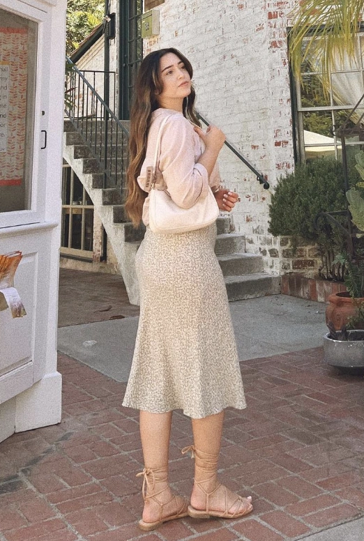 A floral midi skirt in soft beige with a delicate pattern, styled casually for warm weather, perfect for outdoor gatherings.