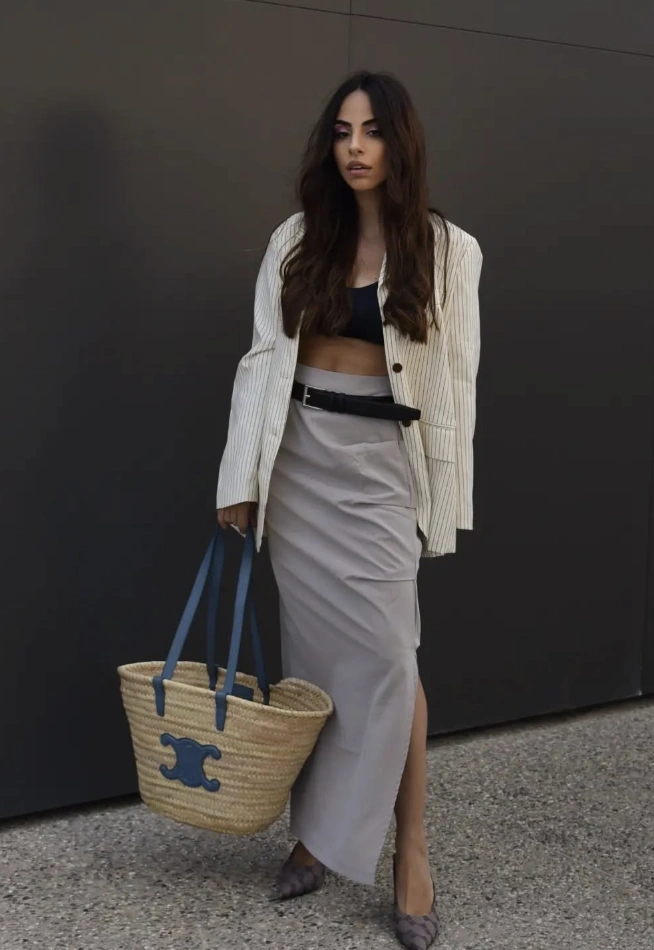 Grey maxi skirt paired with a striped blazer, featuring a high slit. Ideal for casual outings or daytime events.