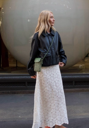 Long white crochet skirt with intricate patterns, paired with a stylish black leather jacket for a trendy, casual look.