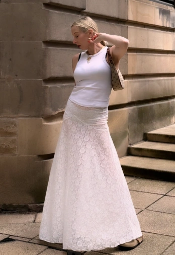 Flowing lace maxi skirt in white paired with a fitted white tank top, perfect for casual outings or summer events.
