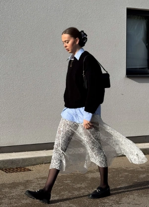 A layered outfit featuring a white lace skirt, black oversized sweater, and light blue shirt, ideal for casual outings.