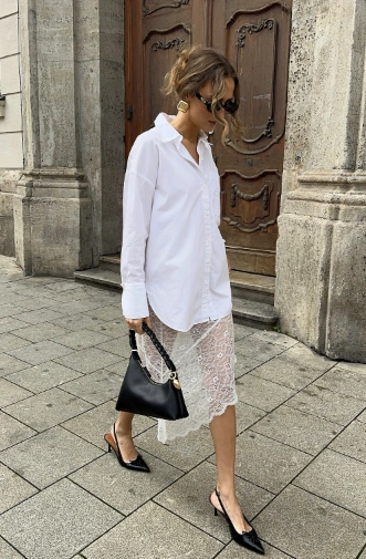 Woman wearing a white lace skirt layered over a button-up shirt; perfect for casual outings or brunch.