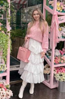 A white ruffled maxi skirt paired with a pink knitted sweater, suitable for casual outings or brunch events.