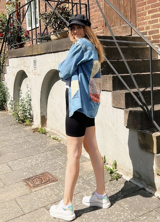 Casual denim oversized shirt with colorful patchwork, paired with black biking shorts; perfect for warm-weather outings.