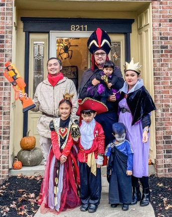 A group in coordinated Halloween costumes featuring varied styles: vibrant dresses, capes, crowns, and accessories, perfect for festive gatherings.