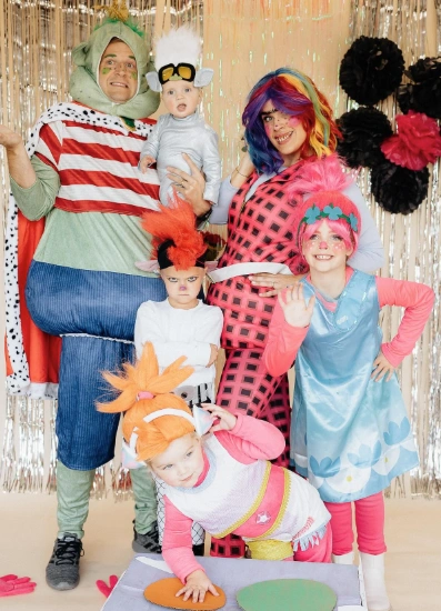 Family in vibrant Halloween costumes; features playful dresses, stripes, and colorful wigs. Perfect for festive gatherings and trick-or-treating.