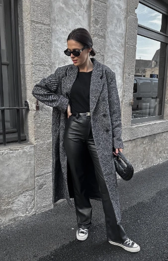 Black leather pants paired with a black top and a long gray houndstooth coat, styled for casual outings.