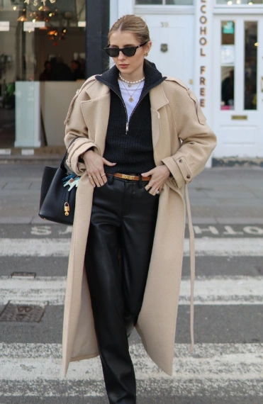 Black leather pants paired with a cozy black sweater and an oversized beige coat, perfect for casual outings or stylish winter events.