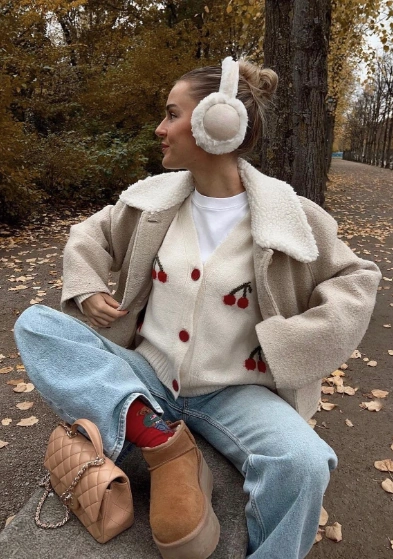 Casual outfit featuring a cream cardigan with cherry embroidery, light wash jeans, and brown Ugg boots, perfect for autumn outings.