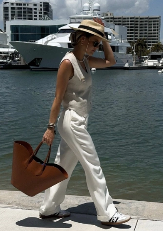 Light beige sleeveless top paired with flowy white trousers and stylish sneakers; perfect for casual summer outings or brunch.