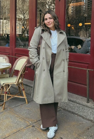 Long beige trench coat over a white t-shirt, paired with brown wide-leg pants and white sneakers; perfect for casual outings.