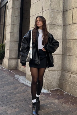 A stylish black leather skirt paired with a white top and oversized jacket, perfect for casual winter outings.