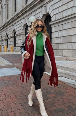 Stylish layered outfit featuring a green turtleneck, black leggings, and a red fringed scarf. Perfect for casual outings.