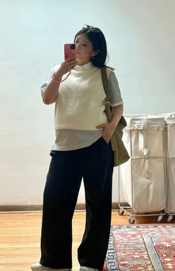 Maternity outfit featuring a cream sleeveless top over a striped shirt, paired with black wide-leg pants, ideal for casual outings.