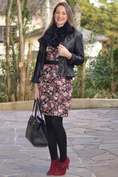 A fitted floral dress in dark tones, layered with a black leather jacket and matching tights, suitable for casual winter outings.