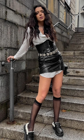 A stylish black leather mini skirt paired with a white oversized shirt and a statement belt, perfect for a night out.