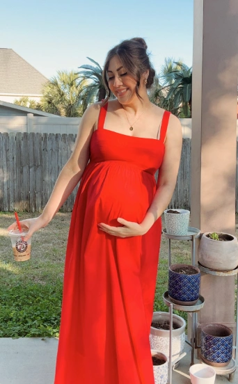 A flowing red maternity maxi dress featuring spaghetti straps and a fitted bodice, perfect for casual outdoor events.