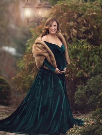 Long emerald green velvet gown with off-shoulder neckline, flowing skirt, and faux fur wrap; perfect for formal events.