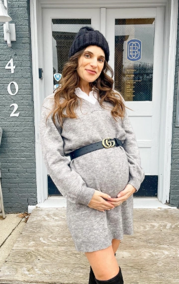 Grey sweater dress with a V-neckline, long sleeves, and a black belt, perfect for casual outings during pregnancy.