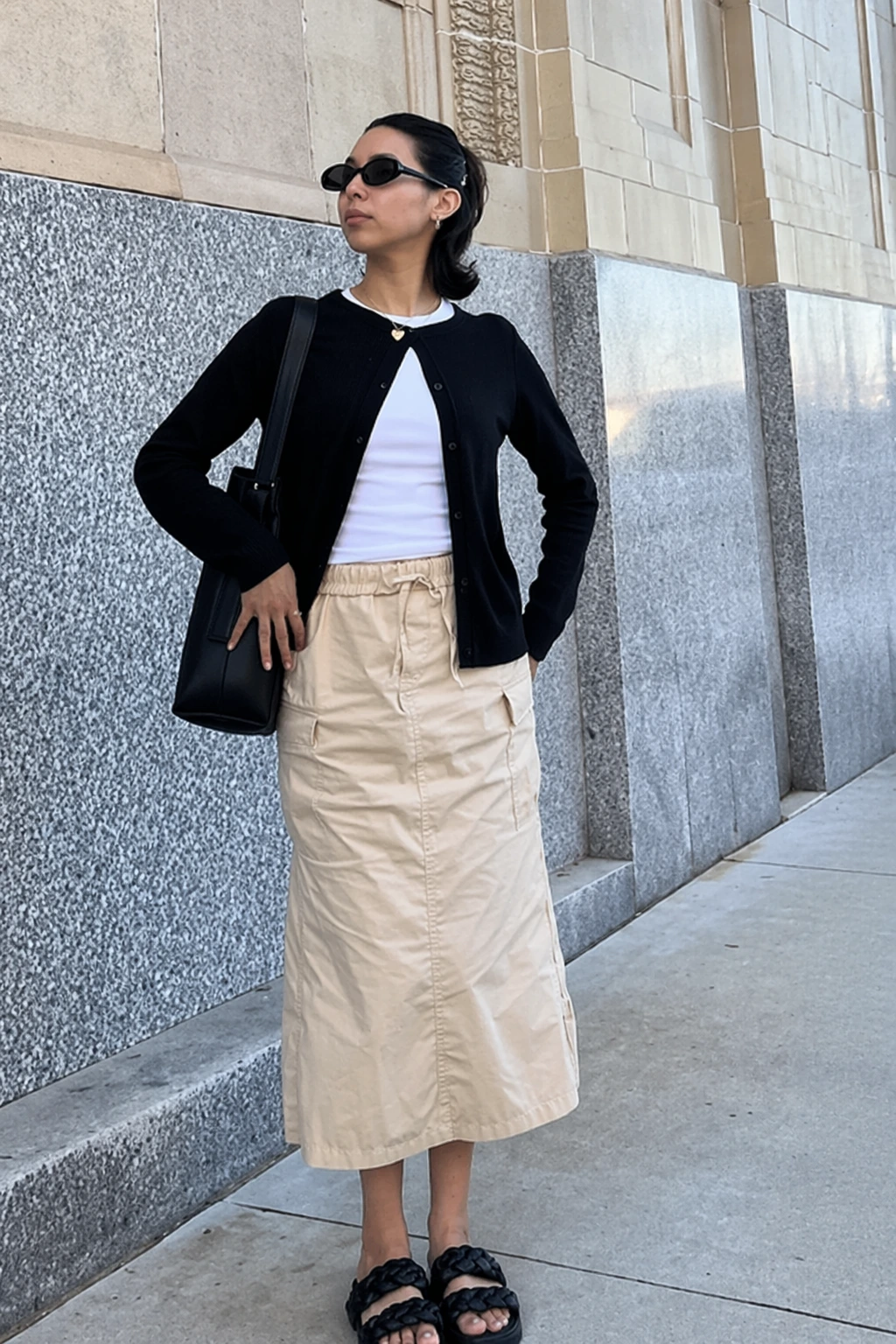 Long cream skirt with cargo pockets, paired with a black cardigan and white top; perfect for casual outings or daytime events.