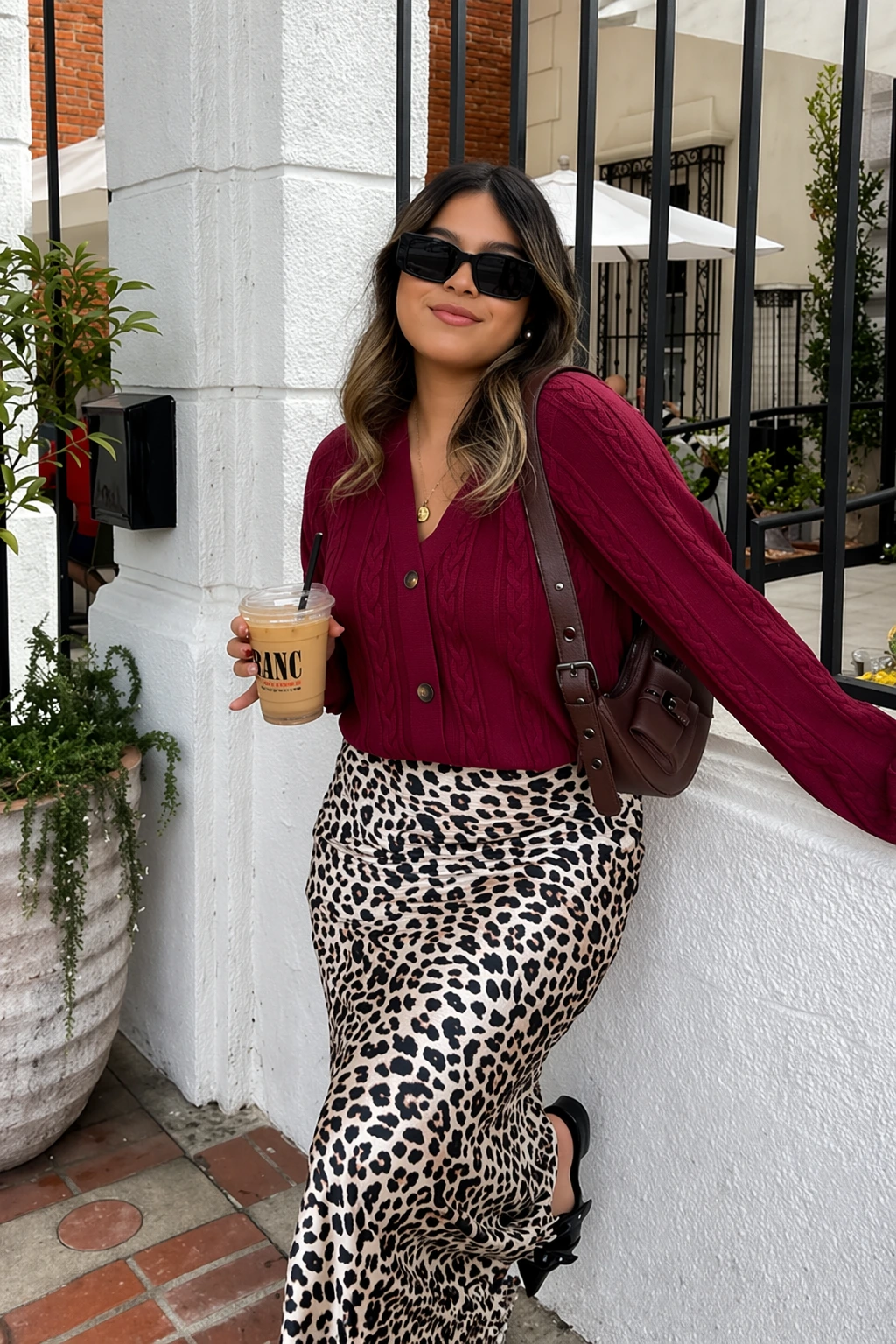 A casual leopard print midi skirt paired with a burgundy cable-knit cardigan, perfect for brunch or a casual outing.