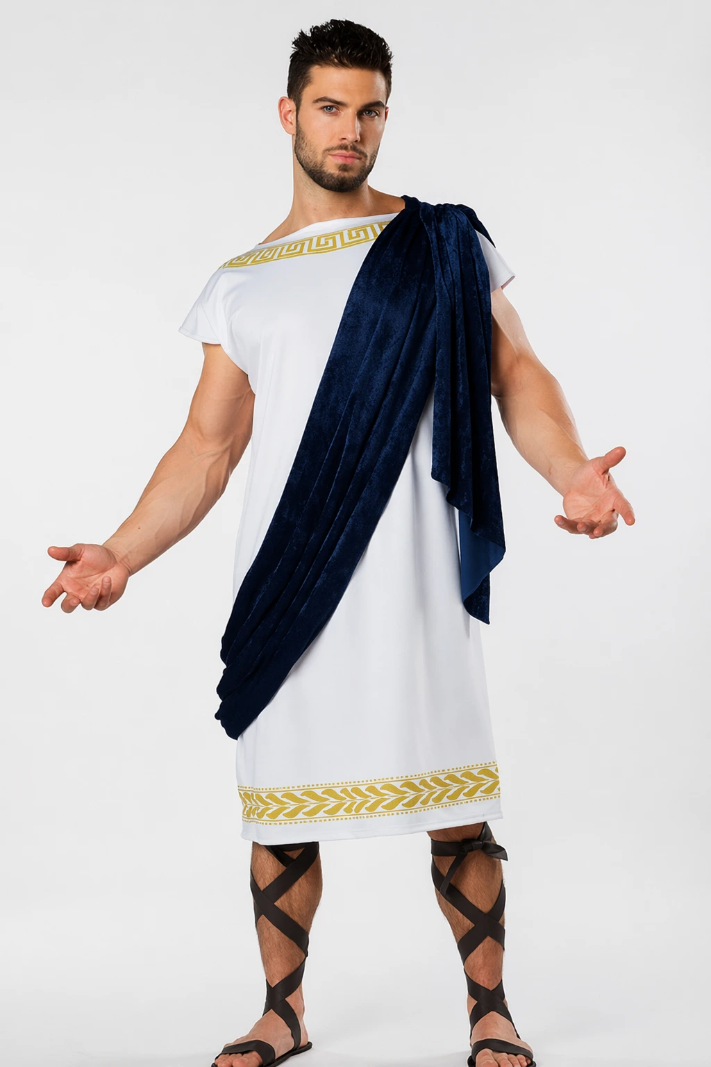 White Roman-style tunic with gold trim, deep blue draped sash, leather sandals, and crisscross leg wraps on a man.