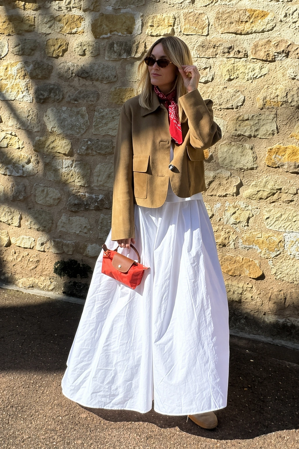 Flowing white maxi skirt paired with a brown cropped jacket, styled casually, perfect for spring outings or brunch.