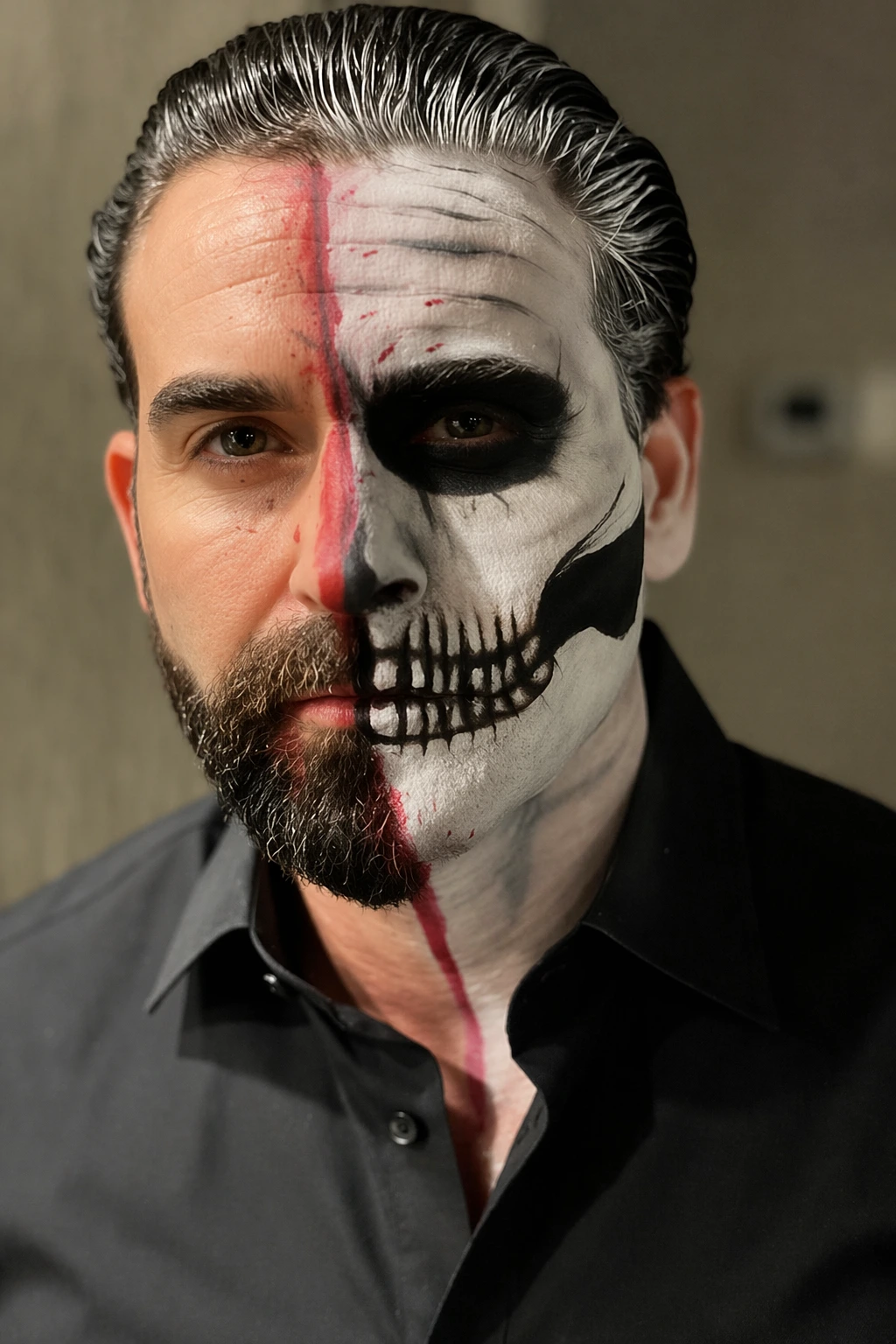 Close-up portrait of bearded man wearing split skull makeup, black button-up shirt, and slicked-back hair.