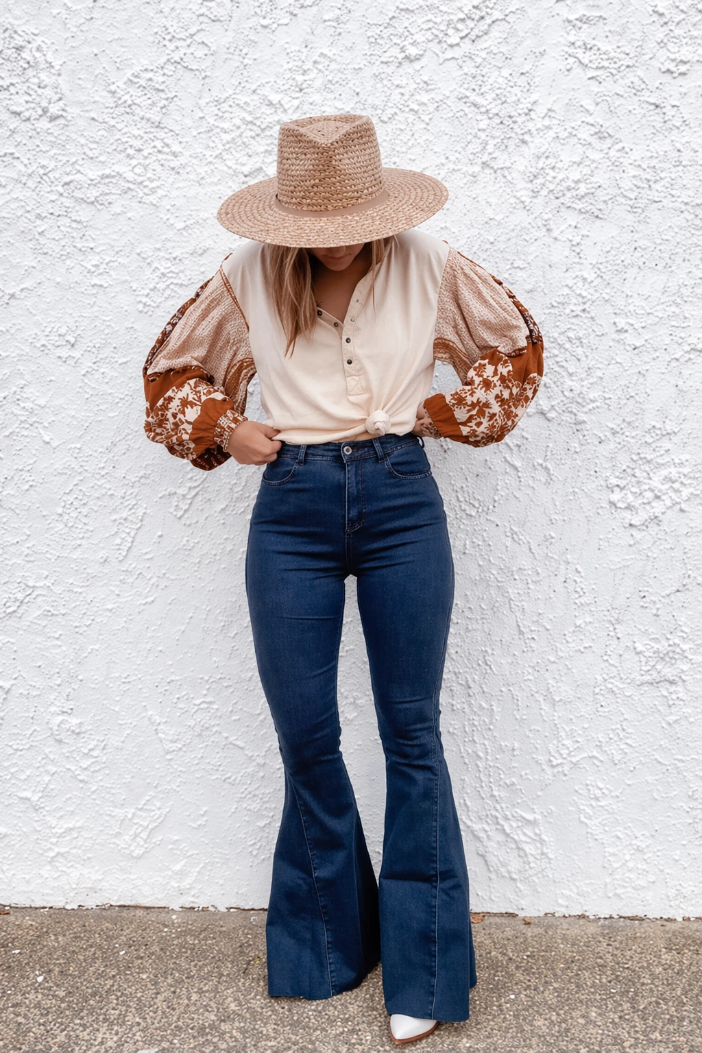 Flare jeans in dark blue paired with a beige button-up blouse featuring floral patterned puff sleeves; perfect for casual outings.