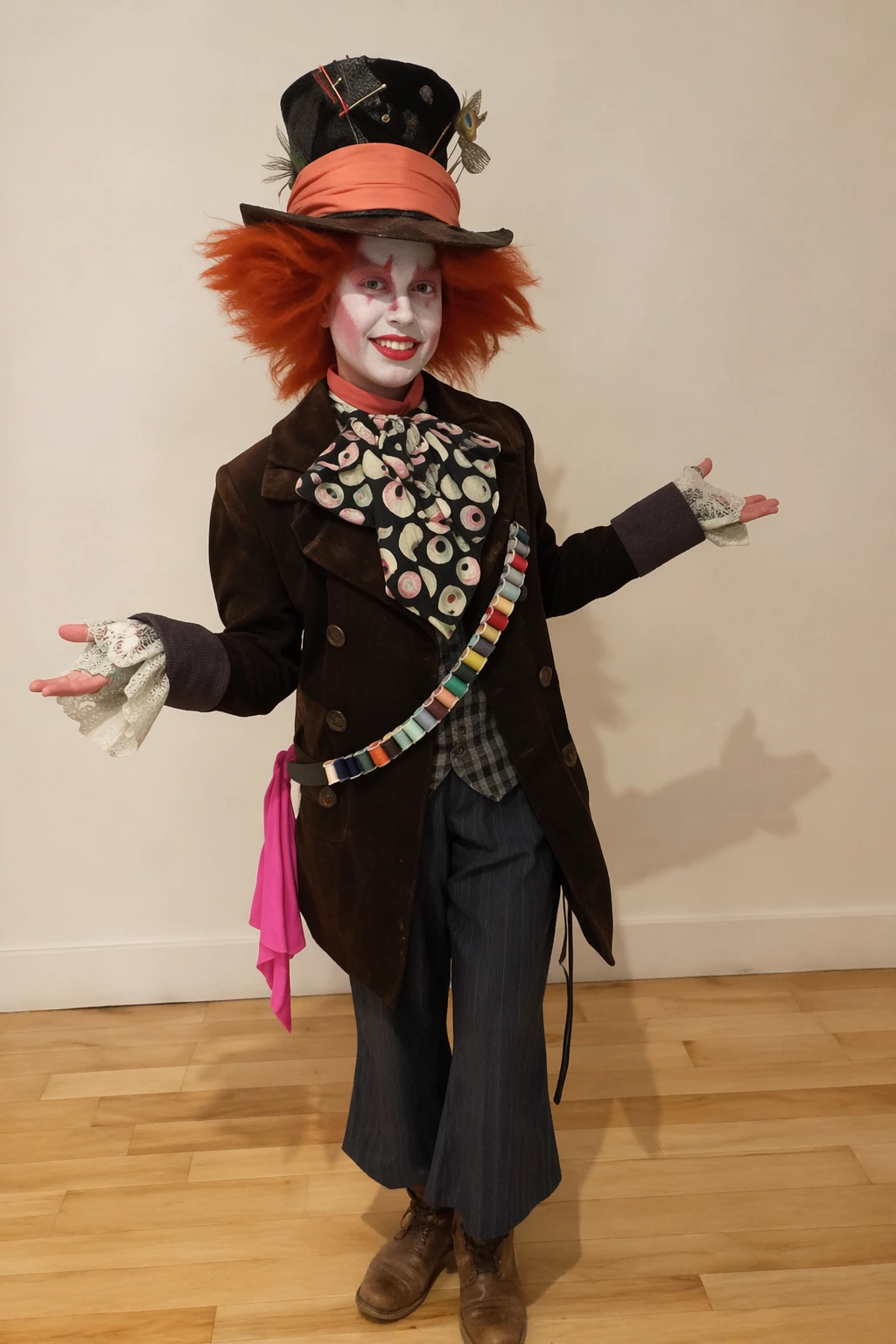 Person in a dark, tailored costume with orange wig, oversized top hat, patterned bow, lace gloves, and striped sash.