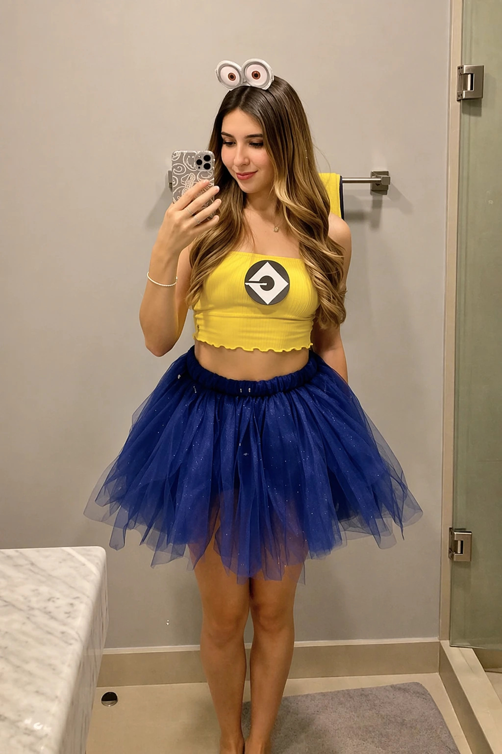 Young woman poses in a bathroom wearing a yellow tube top, blue tulle skirt, and Minion headband.