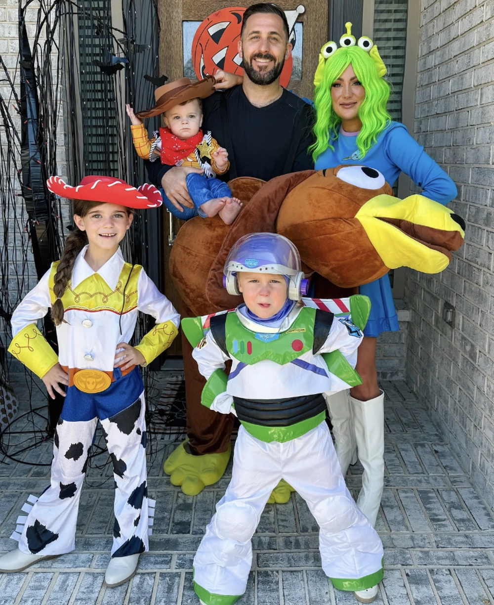 Family of five in Toy Story outfits, featuring Jessie, Woody, Buzz Lightyear, and a large plush Bullseye costume.