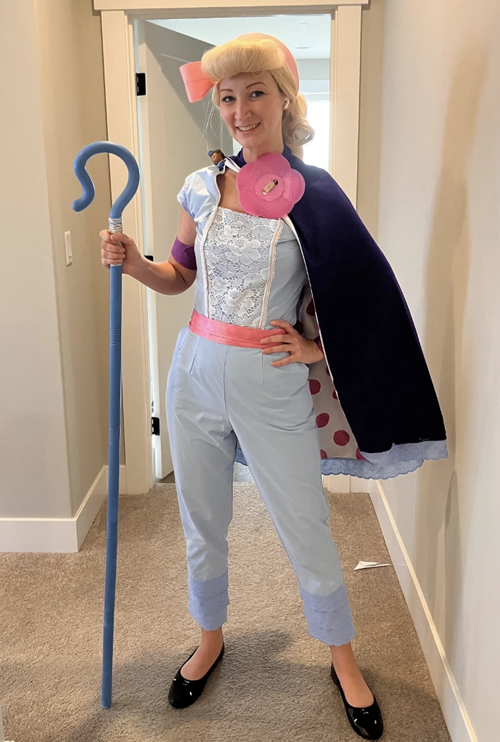 Woman in pale blue Bo Peep outfit holding a blue shepherd's crook and wearing a dark cape.