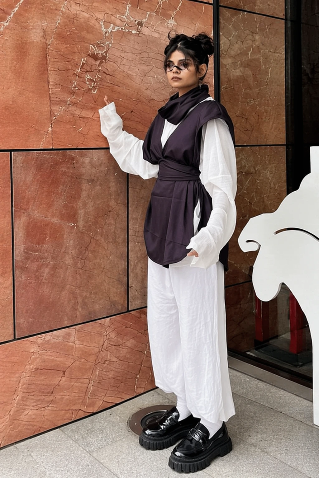 Black-and-white anime-inspired outfit with oversized sleeves, wrapped vest, wide trousers, platform loafers, and hair buns.