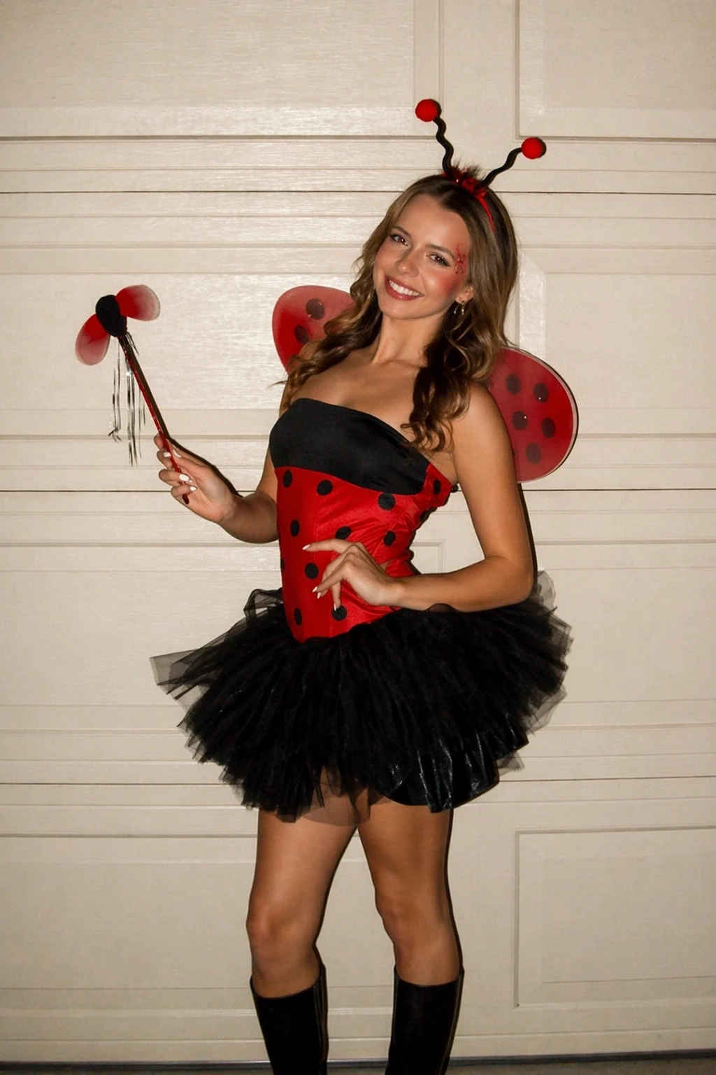 Young woman wearing a red-and-black ladybug costume, black tutu skirt, antenna headband, and translucent spotted wings.